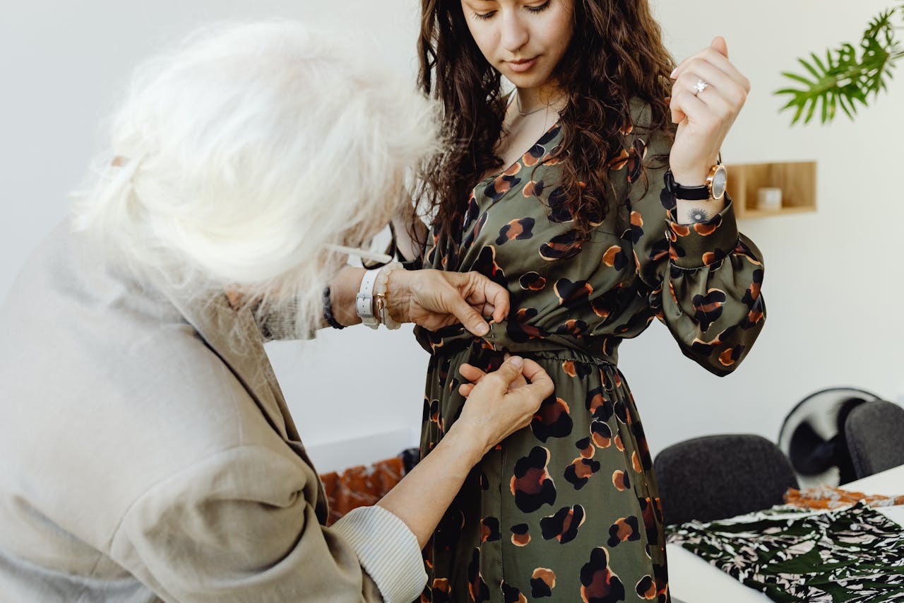 Crafting Captivating Headlines: Your awesome post title goes here Senior woman assisting younger woman with dress fitting in tailoring session.